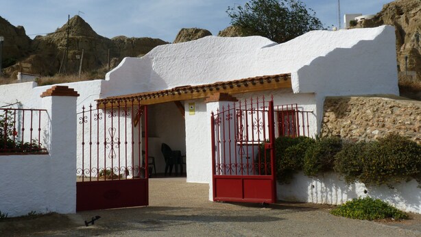 A white building with a red gate and a small patio area.