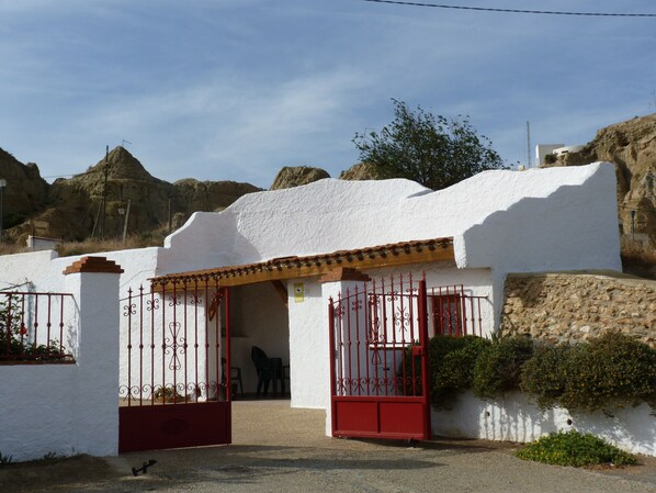 Un bâtiment blanc avec une porte rouge et un petit patio.