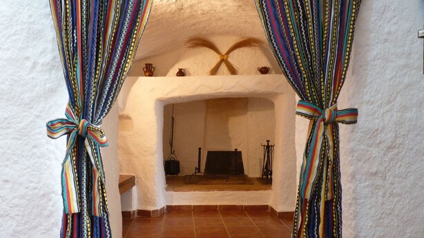 Una habitación con chimenea, paredes blancas y suelo de baldosas.