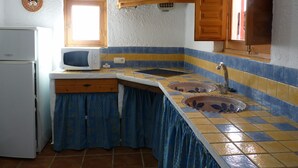 A compact kitchen with a refrigerator, microwave, sink, and wooden cabinets.