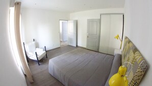 Un dormitorio con cama, una silla y un armario.