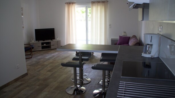 Una cocina moderna con comedor, televisor y cafetera.