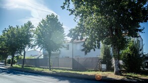 Una calle residencial con una casa blanca, árboles y una cerca.