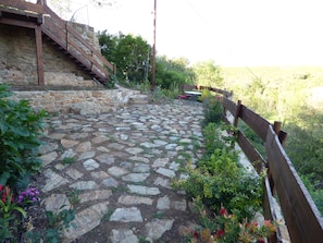 Surrounded by lush greenery, this outdoor space features a stone-paved patio, a wooden staircase, and a wooden fence.