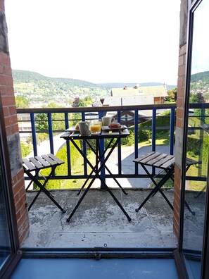 Un balcon avec une table préparée pour le petit-déjeuner, offrant une vue sur un village pittoresque.
