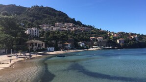 A coastal town with buildings on a hillside, a beach, and clear blue water.