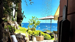 A patio with a view of the ocean, a showerhead, and outdoor furniture.