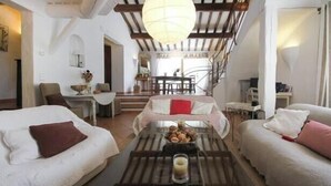 A spacious living area with a high ceiling and exposed beams, a central glass coffee table, and a cozy seating arrangement with two white sofas and a red pillow. - House Gordes. Classified 4☆ tourism (Gordes)