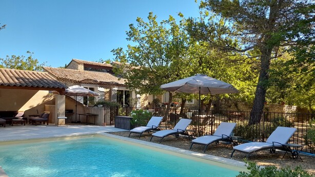 A swimming pool with lounge chairs and umbrellas, surrounded by trees and a stone building. - House Gordes. Classified 4☆ tourism (Gordes)