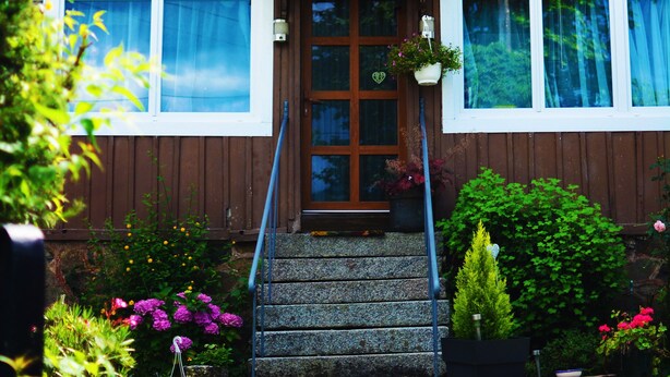 Una casa de madera con balcón, puerta principal y escalones que conducen a la entrada.
