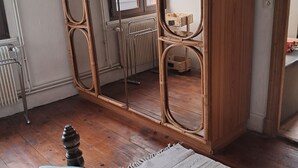Una habitación con un espejo grande, muebles de madera, un radiador y una ventana.