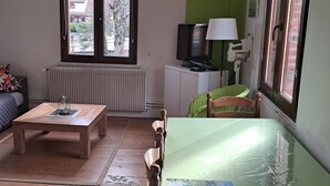Una sala de estar con una mesa de centro de madera, un sofá, un televisor y una lámpara.