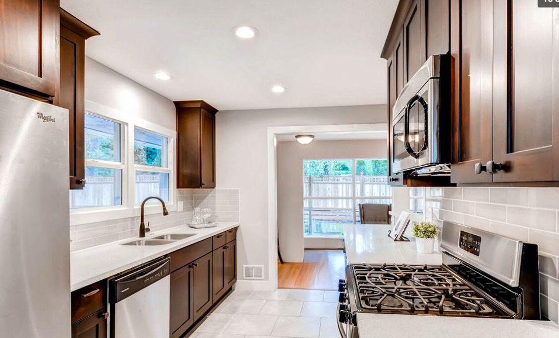 A modern kitchen with stainless steel appliances, wooden cabinets, and a view to the backyard.