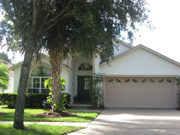 A single-story house with a garage, a front yard with a palm tree, and a well-maintained lawn.