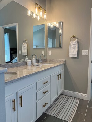 A modern bathroom with a large vanity, double sinks, and a mirror above.