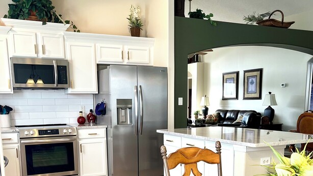 A modern kitchen with white cabinets, stainless steel appliances, and a dining area with a glass table and chairs.
