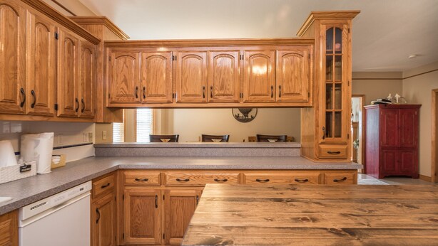 Una cocina con armarios de madera, encimera de granito y lavavajillas integrado.
