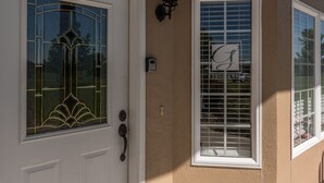 Una casa con una puerta blanca y una ventana con un diseño decorativo en el vidrio.