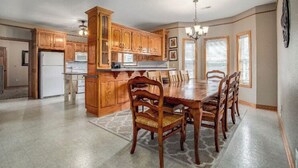 Una cocina amplia con armarios de madera, una isla central y un comedor con sillas.