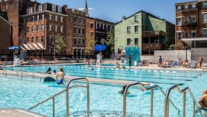 Piscina pública con múltiples carriles, rodeada de edificios urbanos.