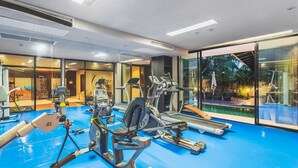 A gym with exercise equipment, a pool, and large windows. - Condo in Bangtao in Kris Condo - Unit402 (Choeng Thale)