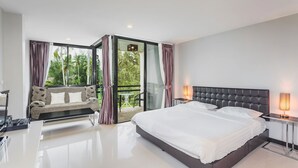 A modern bedroom with a large bed, a sofa, and a balcony with a table and chairs. - Condo in Bangtao in Kris Condo - Unit402 (Choeng Thale)