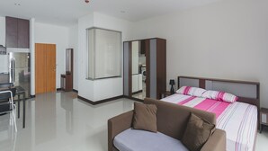 A modern hotel room with a bed, a sofa, a mirror, a wardrobe, and a kitchenette. - Condo in Karon in Chic Condo - Unit A108 (Karon)