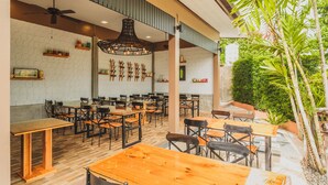A spacious indoor dining area with wooden tables and chairs, a ceiling fan, and a wall decorated with wooden utensils. - Condo in Karon in Chic Condo - Unit A108 (Karon)