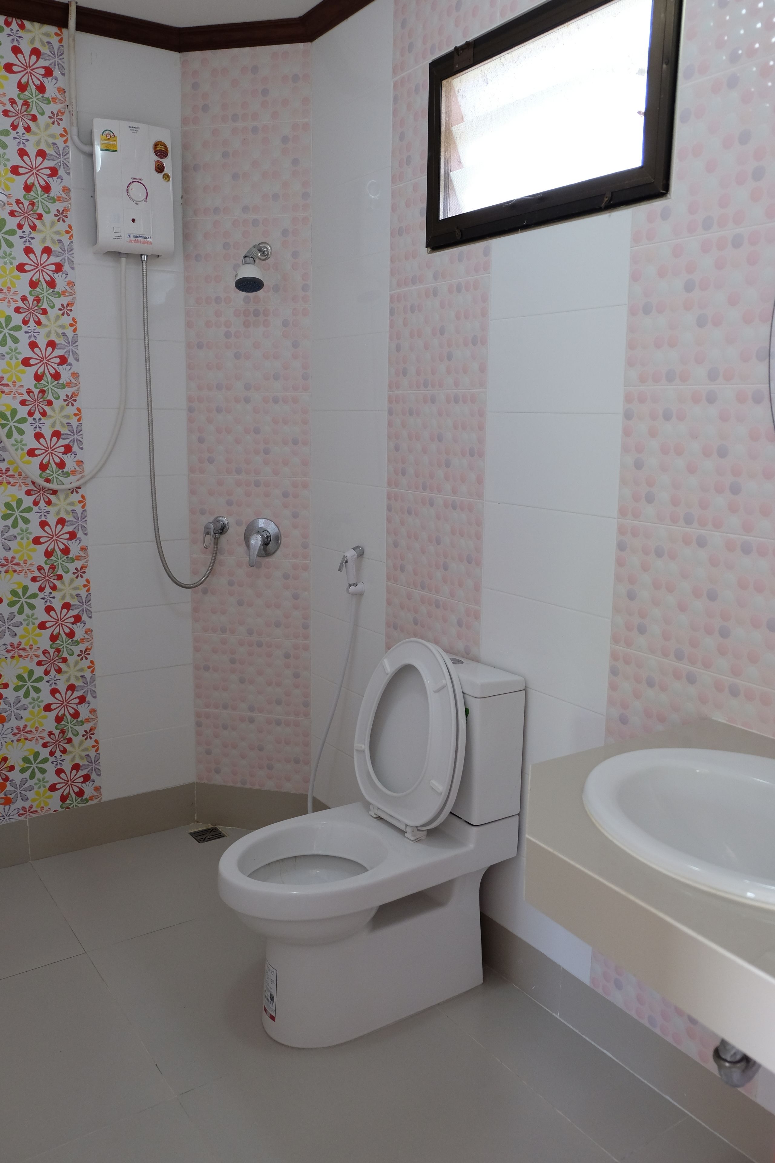 A bathroom with a toilet, a shower, and a sink.