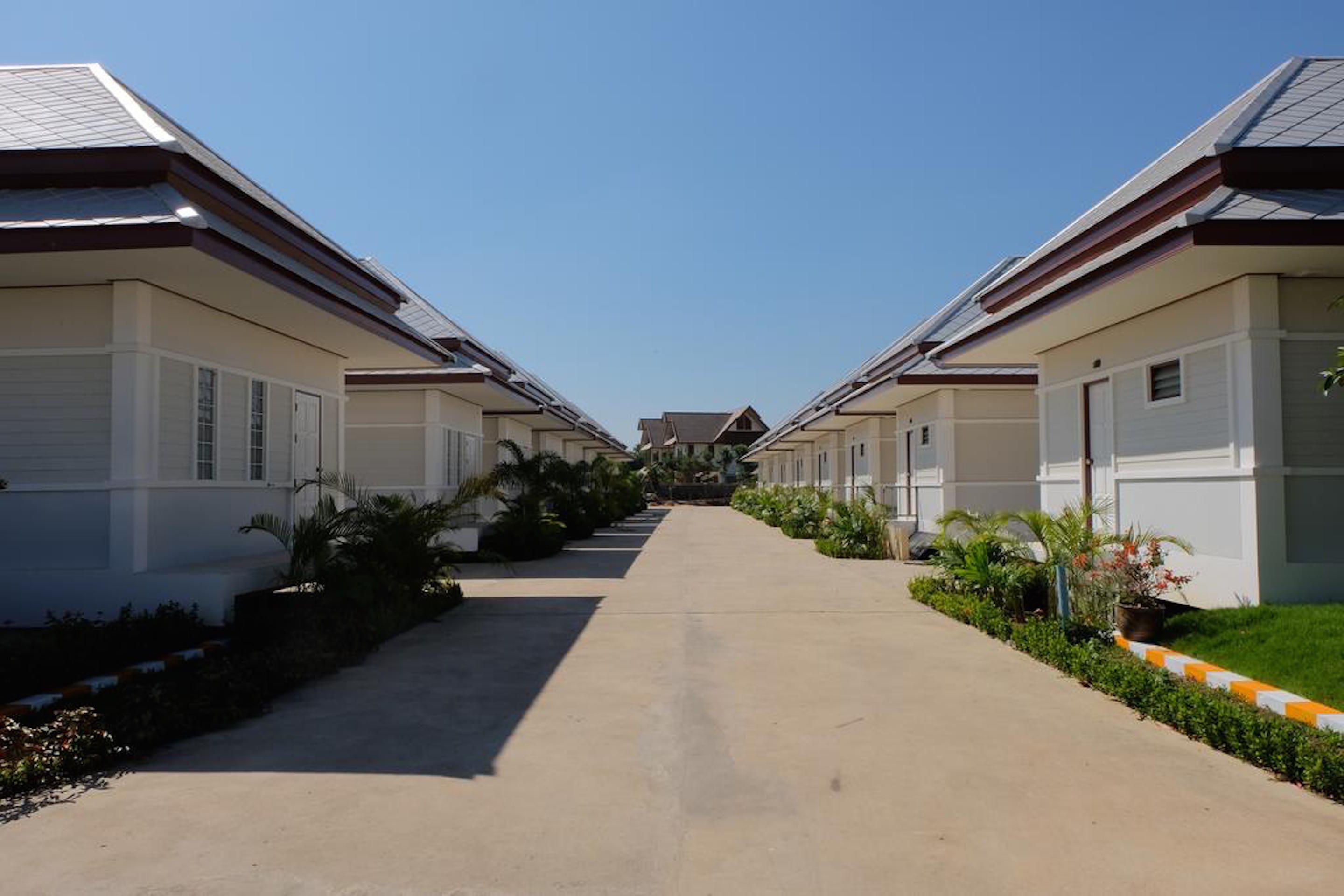 Uma fileira de edifícios modernos, térreos, com um caminho central.