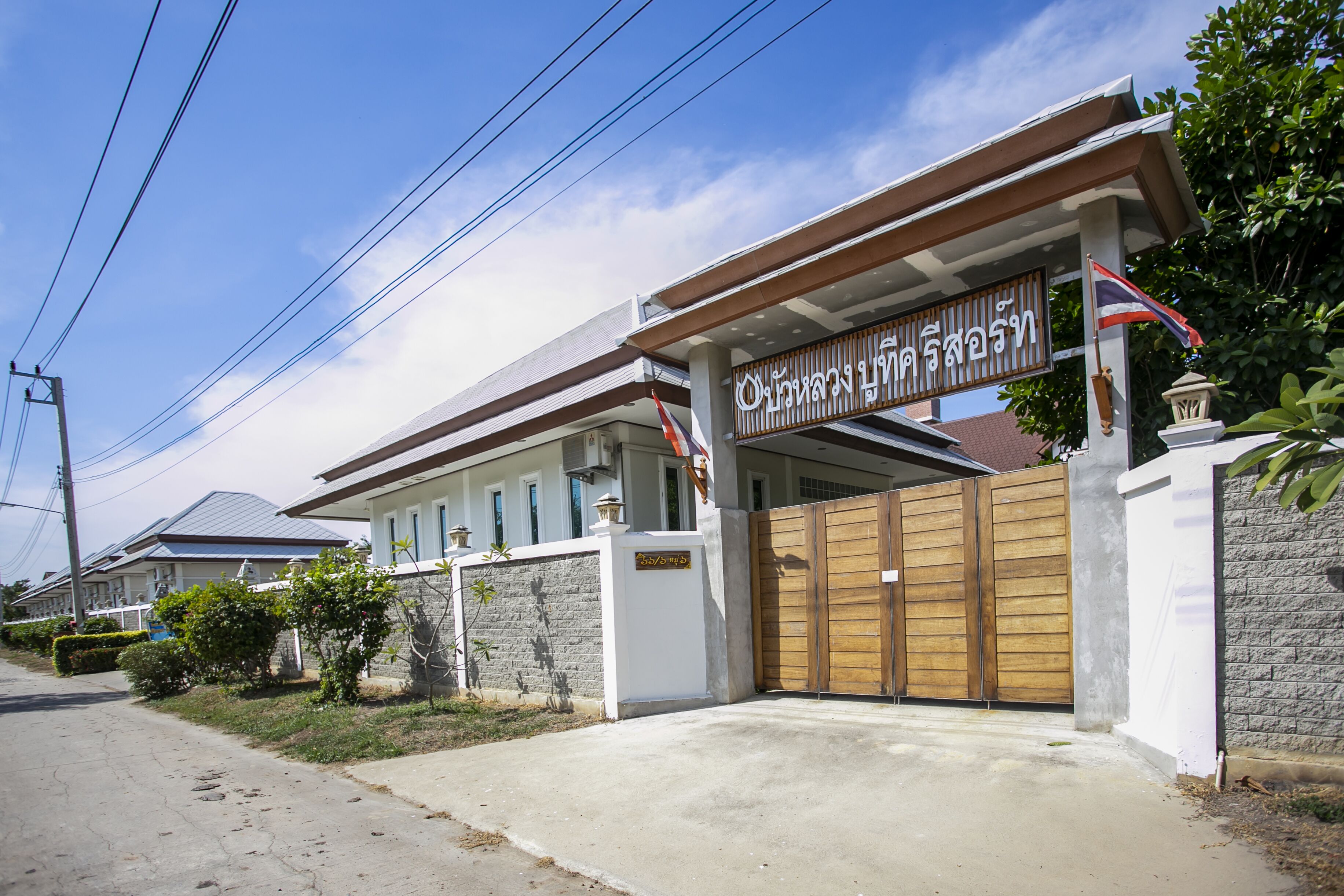 A residential building with a gated entrance, a covered porch, and a sign with Thai script.