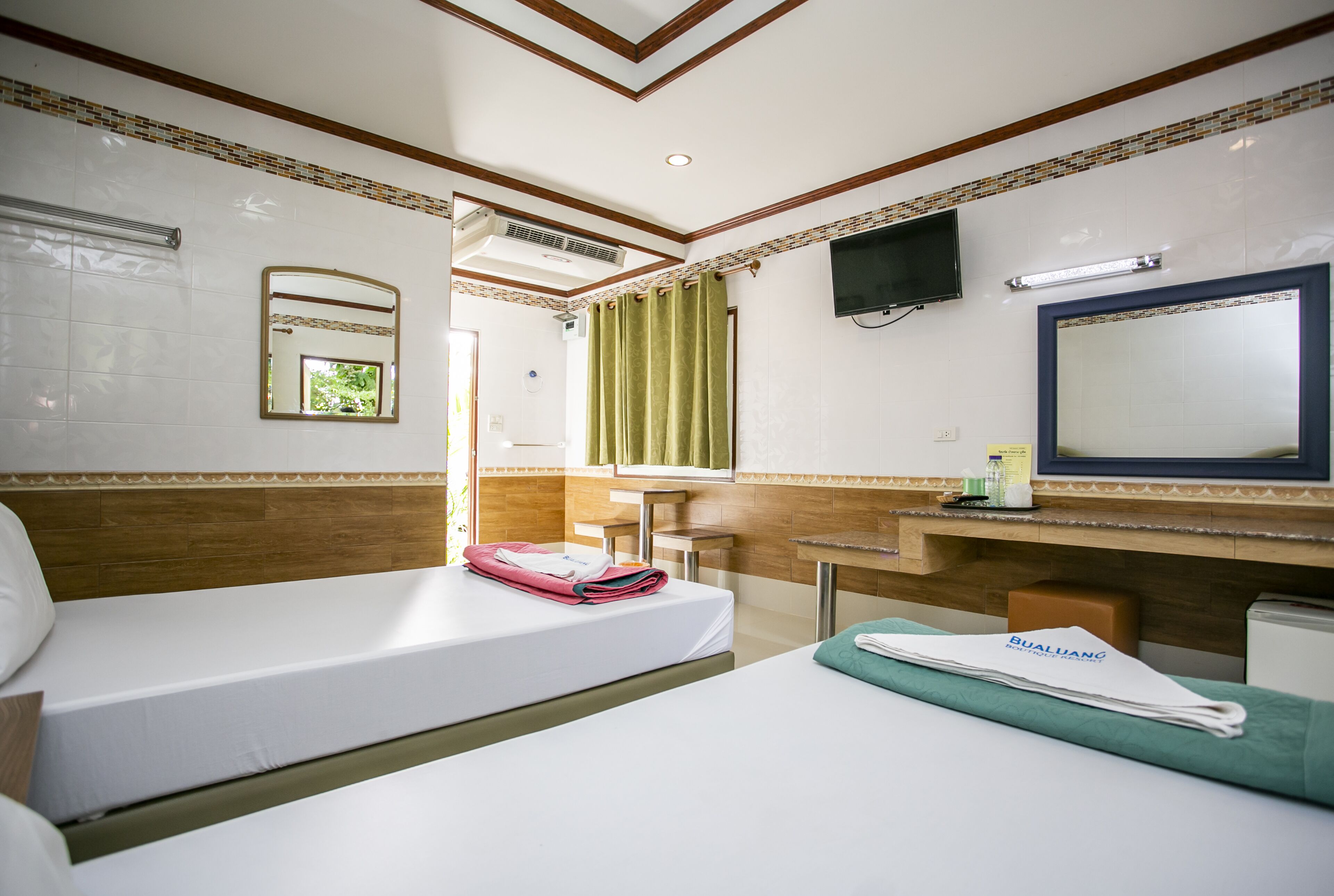 A hotel room with two beds, a bathroom, and a TV mounted on the wall.