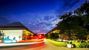Rua ao crepúsculo com uma fonte, casas e céu limpo.