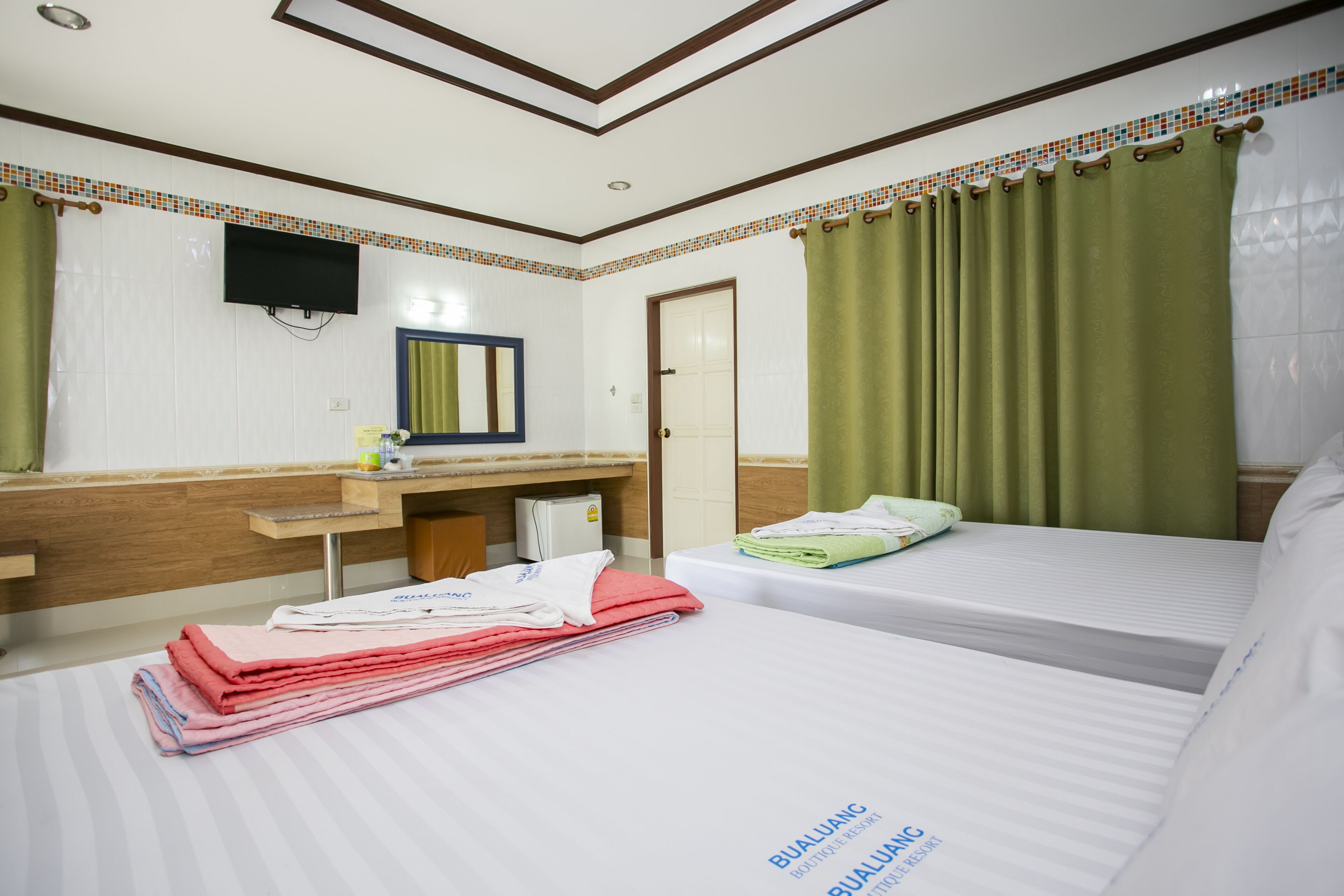 A hotel room with two beds, a bathroom, a flat-screen TV, and a small desk with a mirror.
