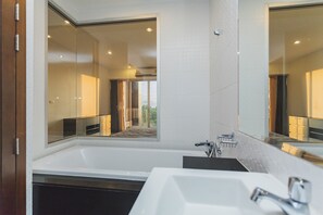 A modern bathroom with a large bathtub, a separate sink, and a mirror.
