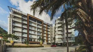 A modern multi-story residential building with balconies, a parking area, and palm trees. - Condo in Karon in Chic Condo - Unit A609 (Karon)
