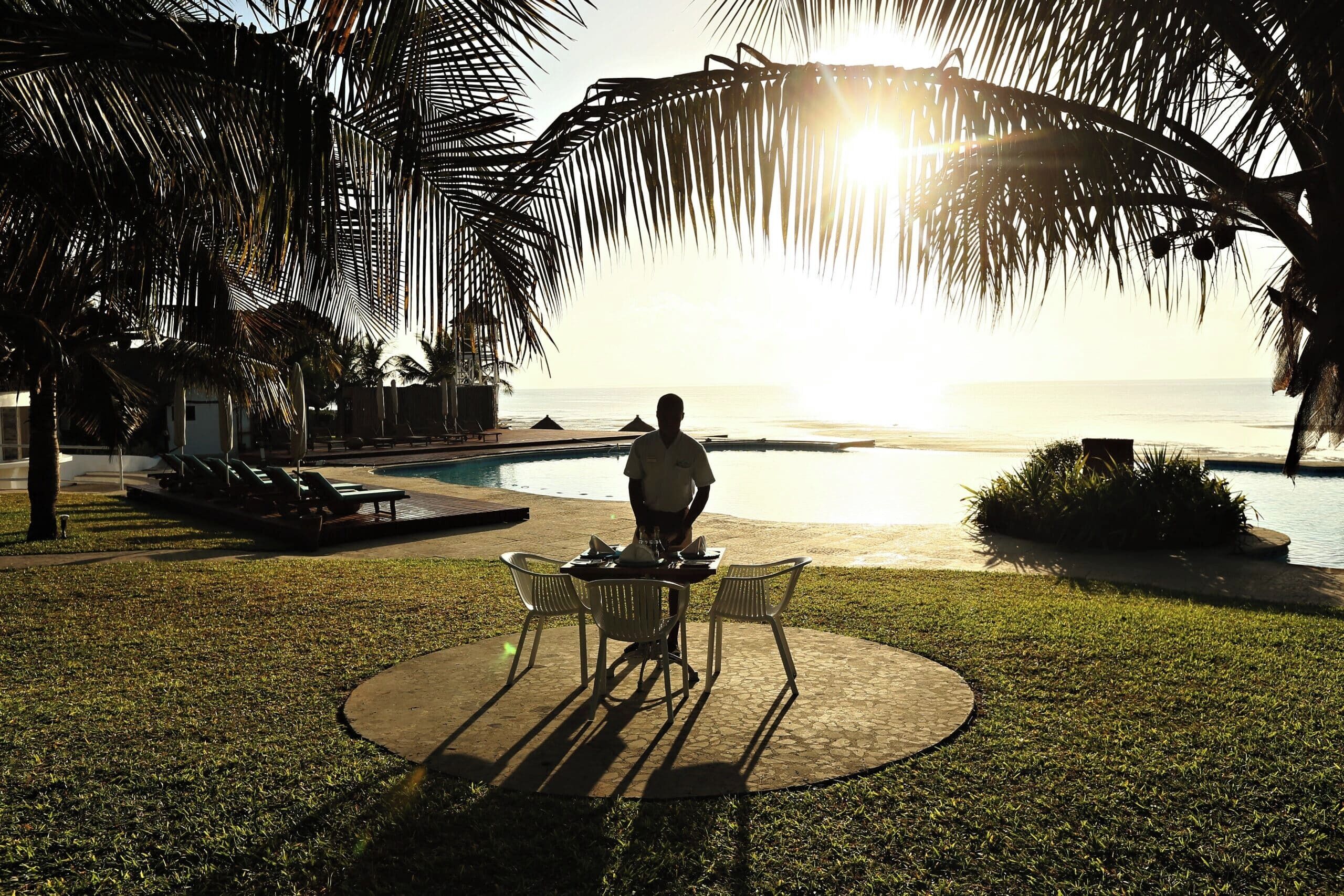 Une personne est assise à une table, avec vue sur l’océan et une piscine en arrière-plan.