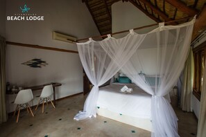 Relax in a serene space with a four-poster bed, wooden desk, and air conditioning for a comfortable stay.