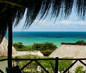 Escape to a serene oceanfront retreat surrounded by lush greenery and thatched-roof structures.