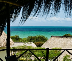 Escape to a serene oceanfront retreat surrounded by lush greenery and thatched-roof structures.