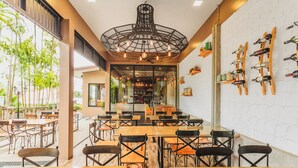 A restaurant with wooden tables and chairs, a large chandelier, and wine racks on the wall. - Condo in Karon in Chic Condo - Unit B708 (Karon)