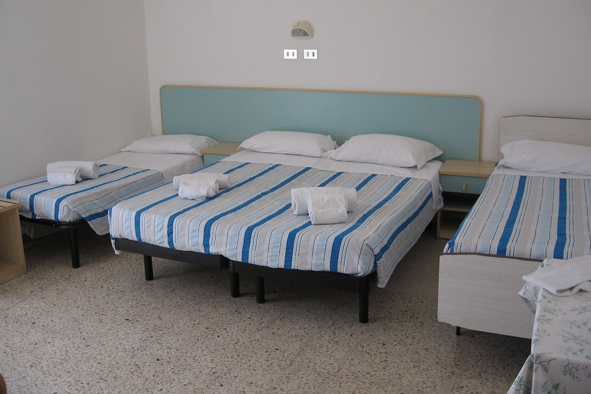 A hotel room with two beds, each with striped bedding and white pillows.