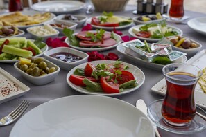 Una mesa servida con diversos platos, entre ellos ensaladas, quesos y un vaso de bebida roja.