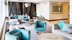 A modern hotel lobby with a high ceiling, a glass staircase, and contemporary furniture. - Withus Condotel at Sea Residences (Pasay)