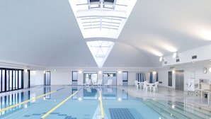 A large indoor swimming pool with clear lanes, a sunroof, and a seating area with tables and chairs. - Rhino Hotel Kyoto (Kyoto)