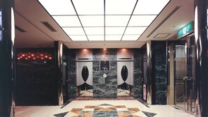 A modern elevator with a geometric patterned floor, a marble wall, and a ceiling with recessed lighting. - Rhino Hotel Kyoto (Kyoto)