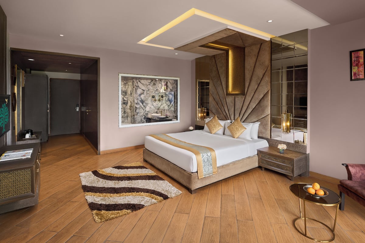 A modern bedroom with a large bed, a nightstand, a chair, and a mirror.