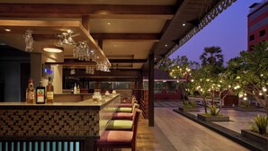 Una zona de bar con salpicadero de azulejos, varios taburetes y una amplia variedad de botellas.