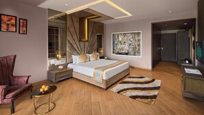 Un dormitorio moderno con una cama grande, un tocador con espejo, un rincón de descanso con una silla y una obra de arte grande en la pared.