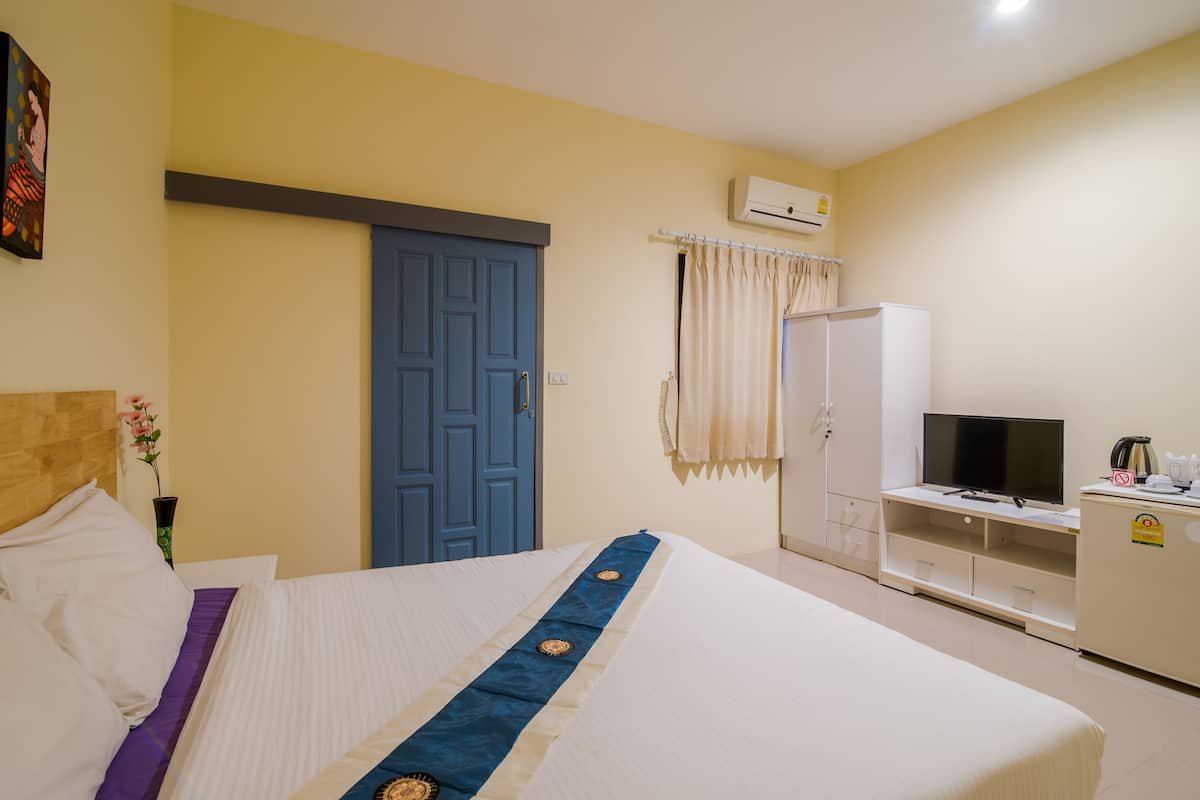 Una habitació d'hotel amb un llit, una televisió, un armari i un aparell d'aire condicionat.